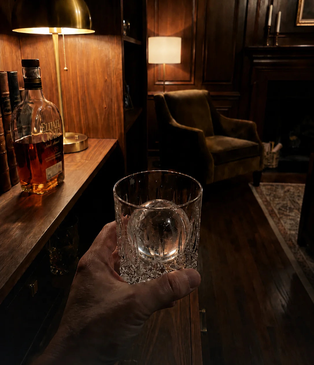 A clear ice sphere served in a crystal glass at a private home bar